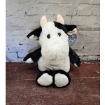 Black-and-white plush cow sitting upright on a wooden surface