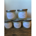 Five labeled soy candles in frosted glass jars with metal lids.
