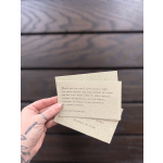 Hand holding two small quote cards over a wooden surface