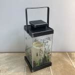Black memorial lantern with a candle inside and floral print panels