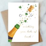 Greeting card with champagne bottle, cork, horseshoes, and clovers