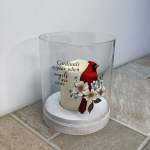 Candle in a glass cloche with a cardinal and flowers
