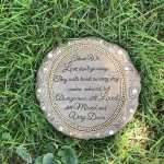 Round memorial plaque with engraved text lying in grass