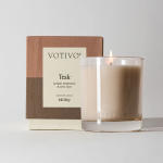 Lit teak-scented candle beside its box
