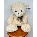 Cream-colored teddy bear with a plaid ribbon sitting on a stool