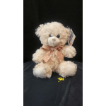 Cream teddy bear with a pink polka-dot bow on a black backdrop