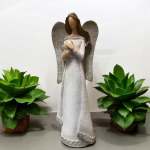Angel figurine in a white dress flanked by two potted succulents