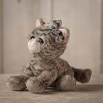 Gray plush cat with a ribbon bow sitting on a neutral surface