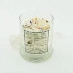Clear glass candle jar with a cream candle and floral specks