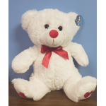 White teddy bear with red nose, red bow, and heart accents on feet sitting on a table