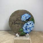 Round memorial plaque with blue flowers and the words "In Loving Memory"