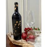Wine bottle beside an empty stemmed glass with pomegranate and berries