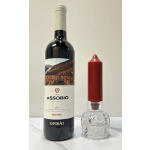Wine bottle beside a red candle in a clear glass holder
