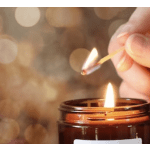 Hand lighting a candle in an amber glass jar