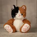 Plush calico cat toy sitting upright with pink paw pads
