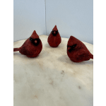 Three red decorative bird figurines on a light surface