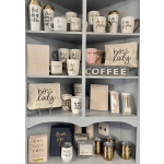Shelf of coffee mugs, tumblers, and gift pouches with motivational sayings