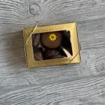 Gold box of chocolates with a small flower decoration on top