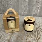 Brown jar candle with engraved wooden lid beside a matching candle in a kraft gift box