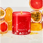 Red candle in a glass holder surrounded by sliced citrus fruit
