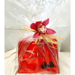 Gift bag with a red candy box topped by a pink orchid