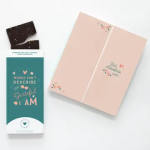Sea salt caramel dark chocolate bar with teal wrapper and peach greeting card with small hearts