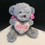 Gray teddy bear holding a heart pillow with the word Amor