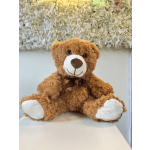 Brown teddy bear with a ribbon sitting in front of a floral wall