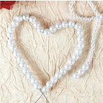 Pearl bead heart decoration on a crinkled beige background