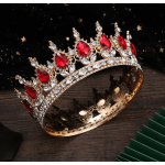 Jeweled gold crown with red and clear stones on a dark surface