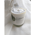 A glass candle labeled Summer Mint on white fabric