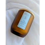 Amber glass candle jar with a wooden lid on white fabric