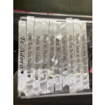 White ribbon strips with gold-lettered Spanish phrases and heart icons.