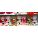 Plush teddy bears holding red roses on a shelf