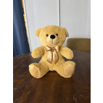 Golden teddy bear with a satin bow sitting on a table