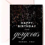 Black birthday card with confetti design and 'Happy Birthday you gorgeous human' text and a pale pink envelope.
