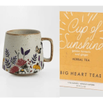 Floral-patterned ceramic mug next to a yellow herbal tea packet labeled Cup of Sunshine