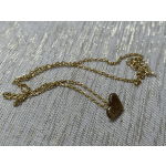 Gold chain necklace with a small heart pendant on textured fabric