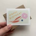 Birthday card with a pink flower design held over a brown envelope
