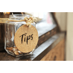 Glass jar with a cork "Tips" tag and coins inside