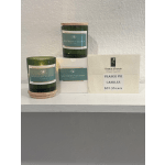 Three green jar candles with wooden lids and a product sign