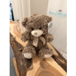 Brown plush teddy bear with a ribbon bow sitting on a wooden surface