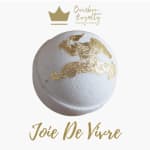 White candle with gold leaf accents and a logo above it