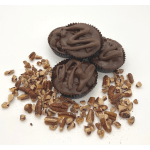 Three chocolate candies topped with pecans on a white surface