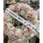 Pink and white floral condolence wreath with a memorial ribbon