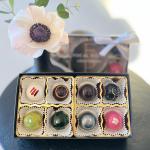 Single pale flower above a box of assorted chocolates