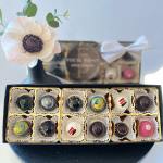 Box of assorted chocolates with a single white flower on top