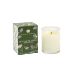 Scented white candle in a clear glass holder beside a green floral-patterned box