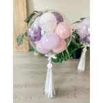 Clear balloon filled with pastel balloons and birthday text on a stand