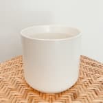White ceramic planter on a woven mat